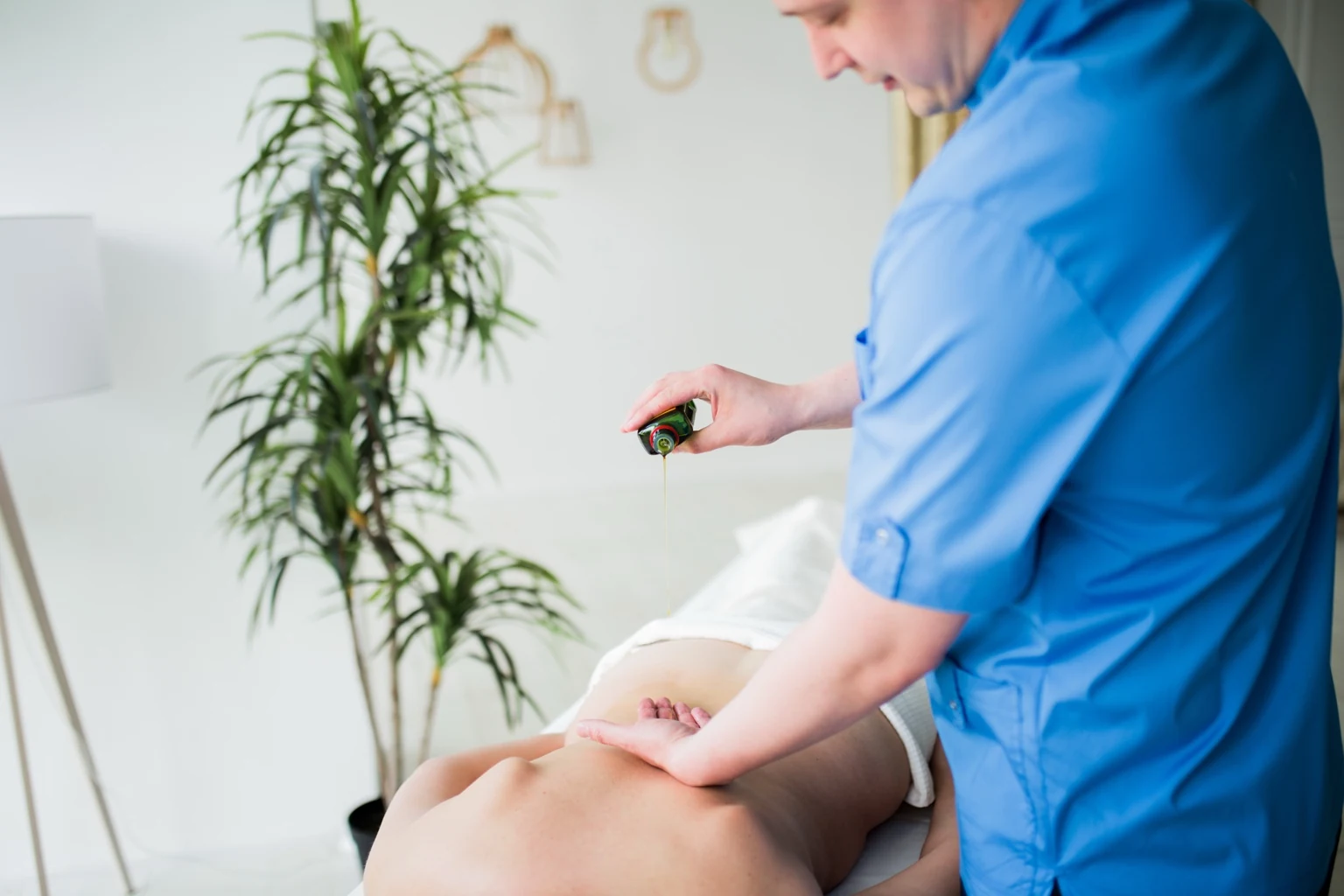 Therapist pouring warm oil before an Ayurvedic Abhyanga massage