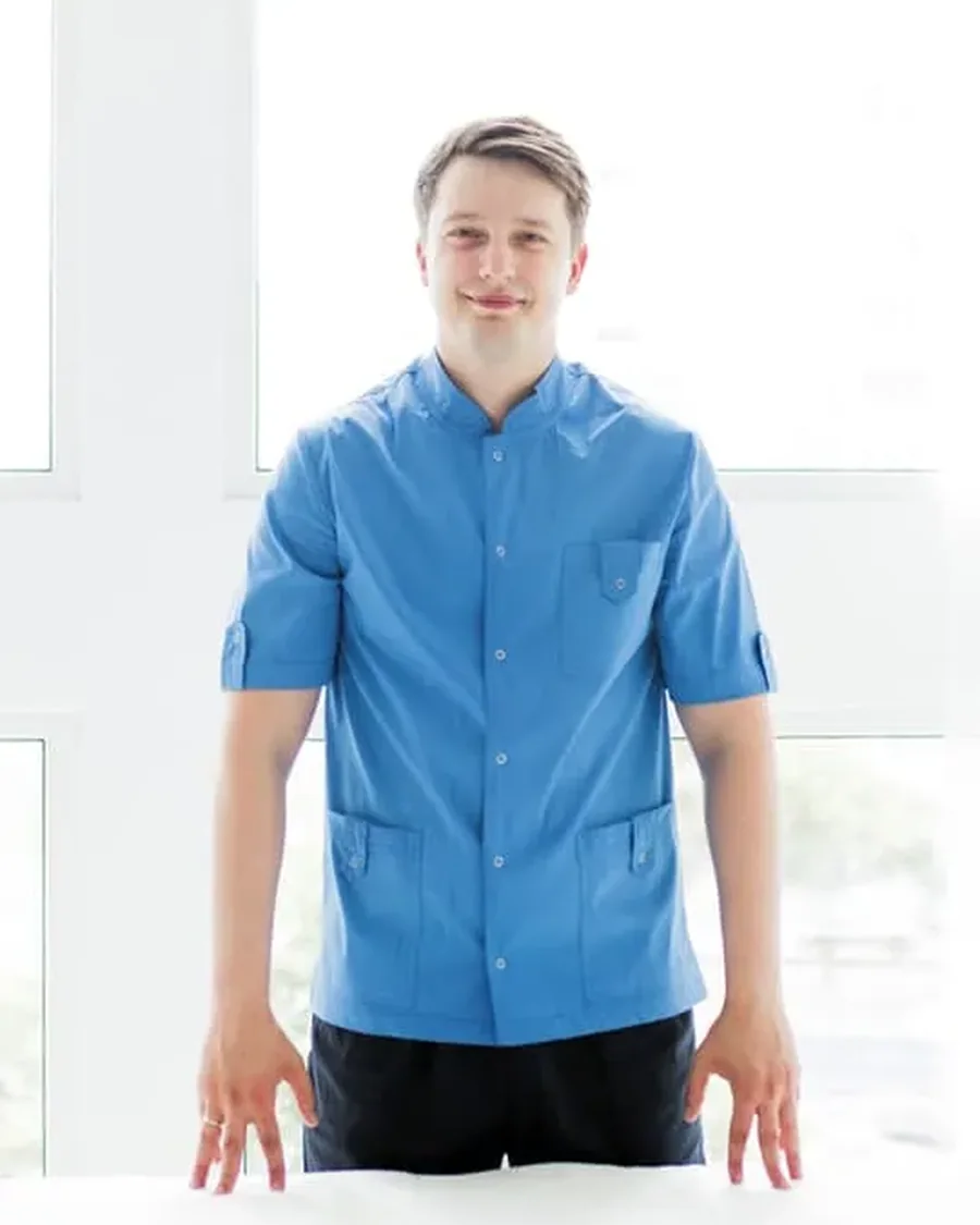 Sergii, principal massage therapist, standing beside a treatment couch